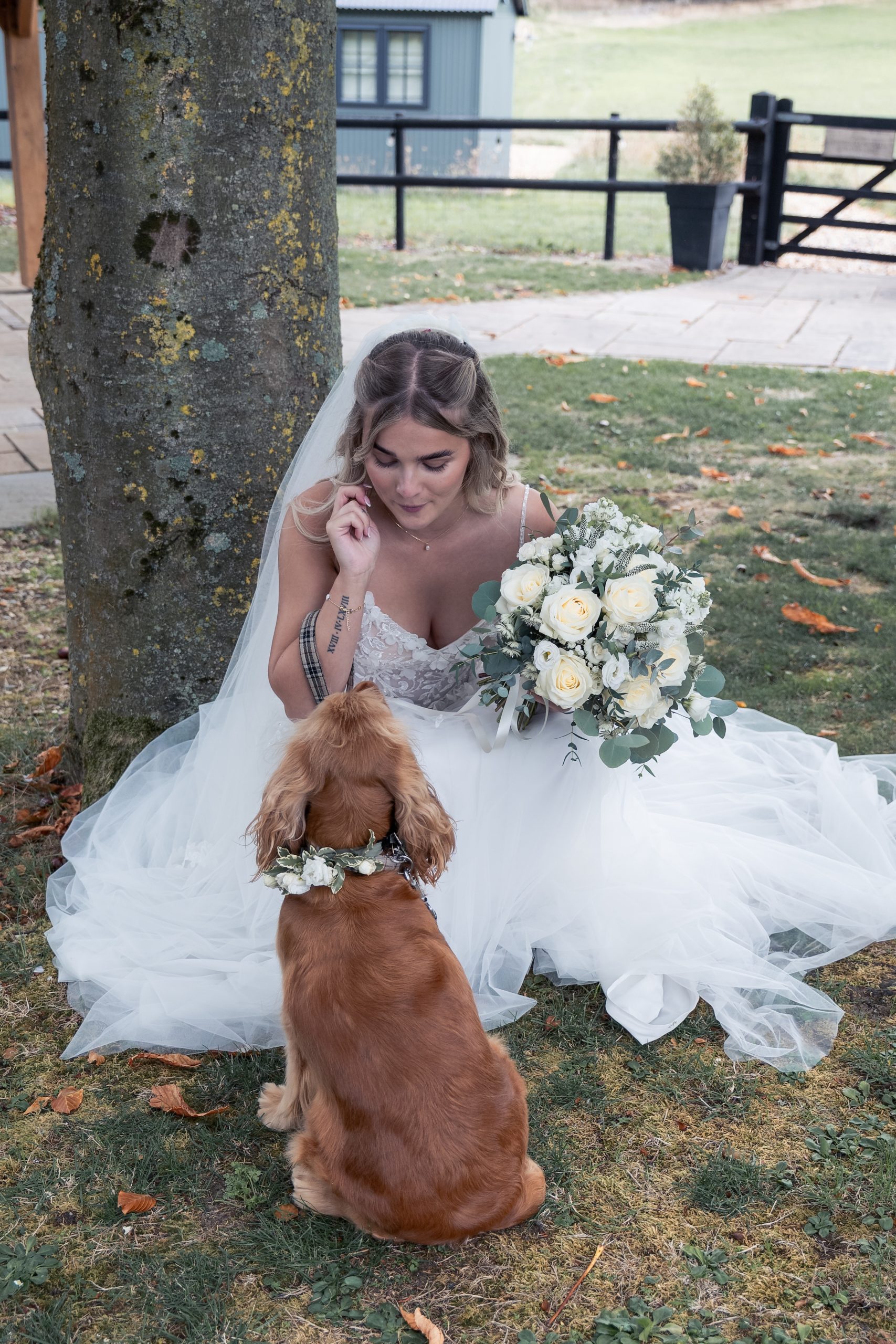 Ella in her wedding gown with her dog wearing a floral collar at Wellington Barn