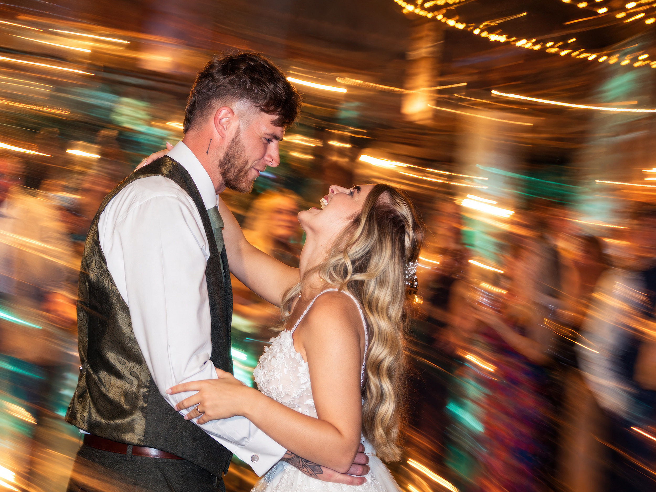 Bride and groom dancing beneath warm lights during their wedding reception