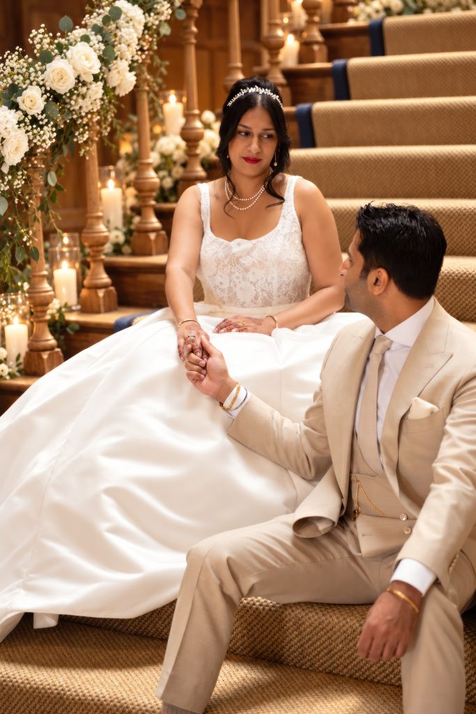 Rosie and Sorab holding hands on the flower-lined staircase at Farleigh House