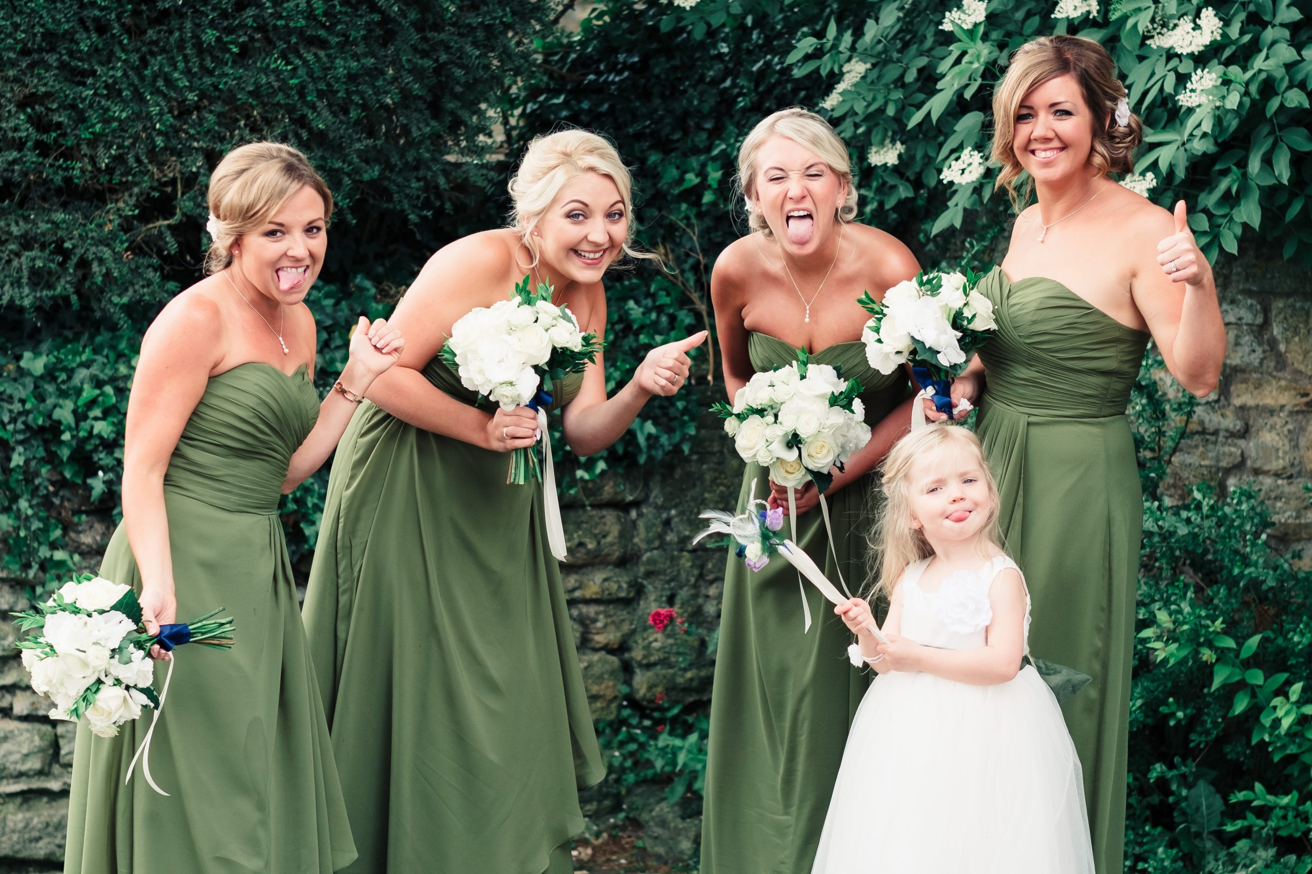 Bridesmaids laughing with bouquets and a young flower girl