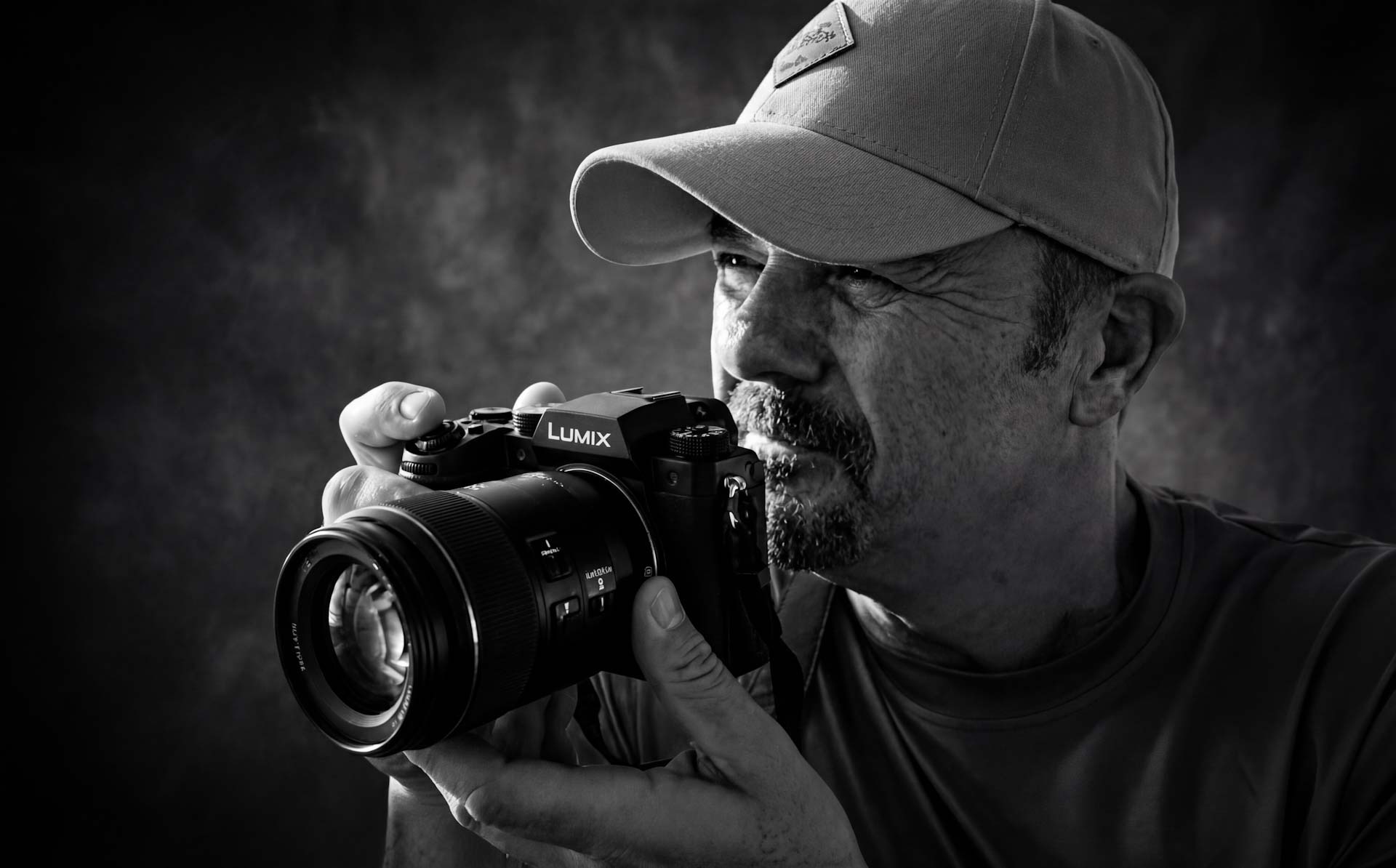 Michael Gane holding his Lumix camera, photographed in black and white