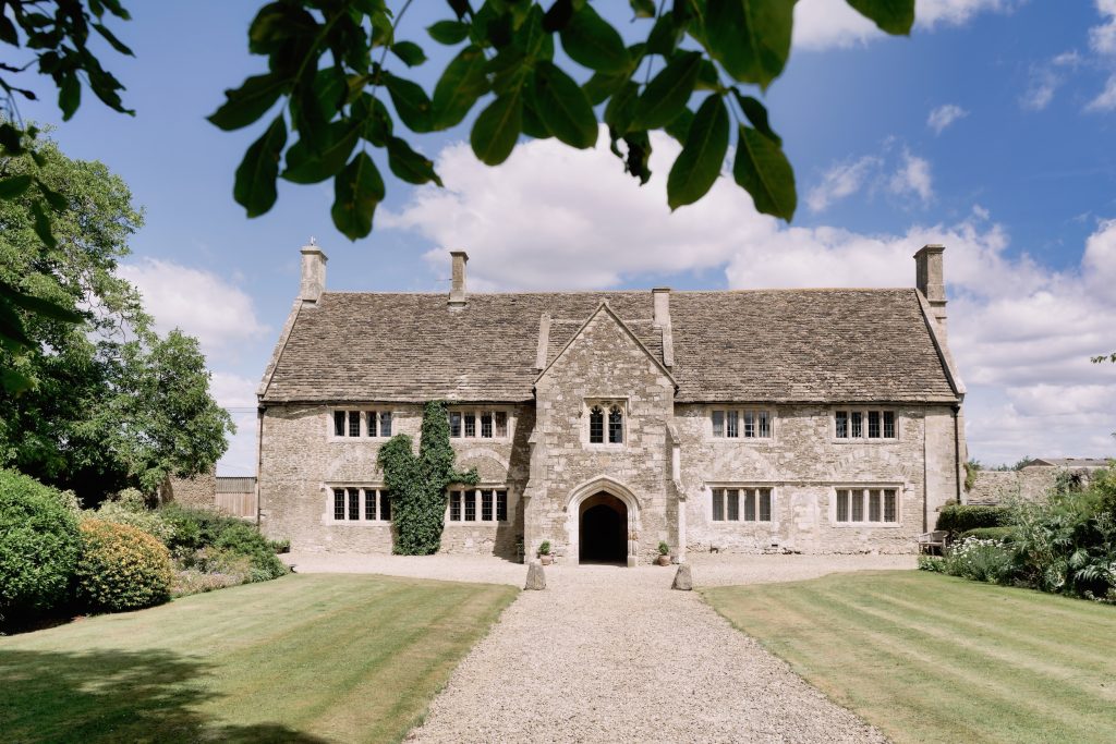 Seymours Court’s historic stone manor house, gravel drive and lawns framed by leafy branches.