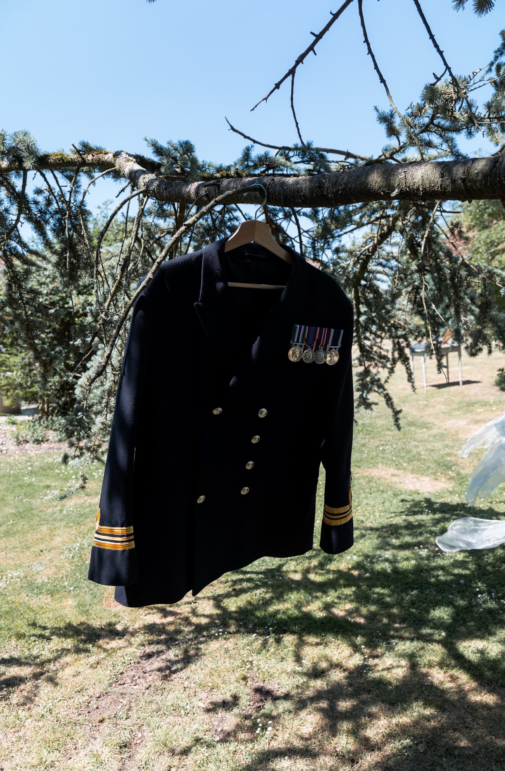 Ross’s dark military dress uniform with medals hanging from a tree in the gardens at Widbrook Grange.
