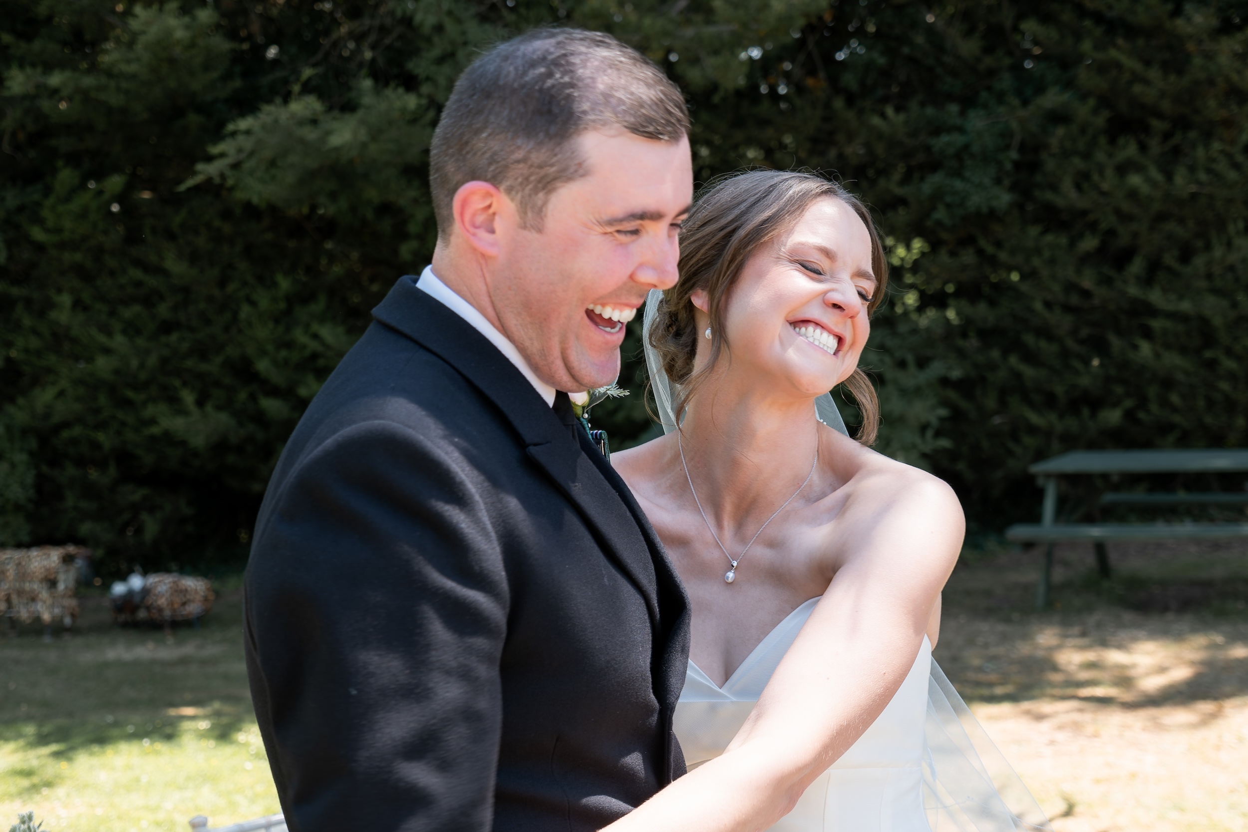 Laura and Ross laughing together in the sunshine during their wedding at Widbrook Grange.